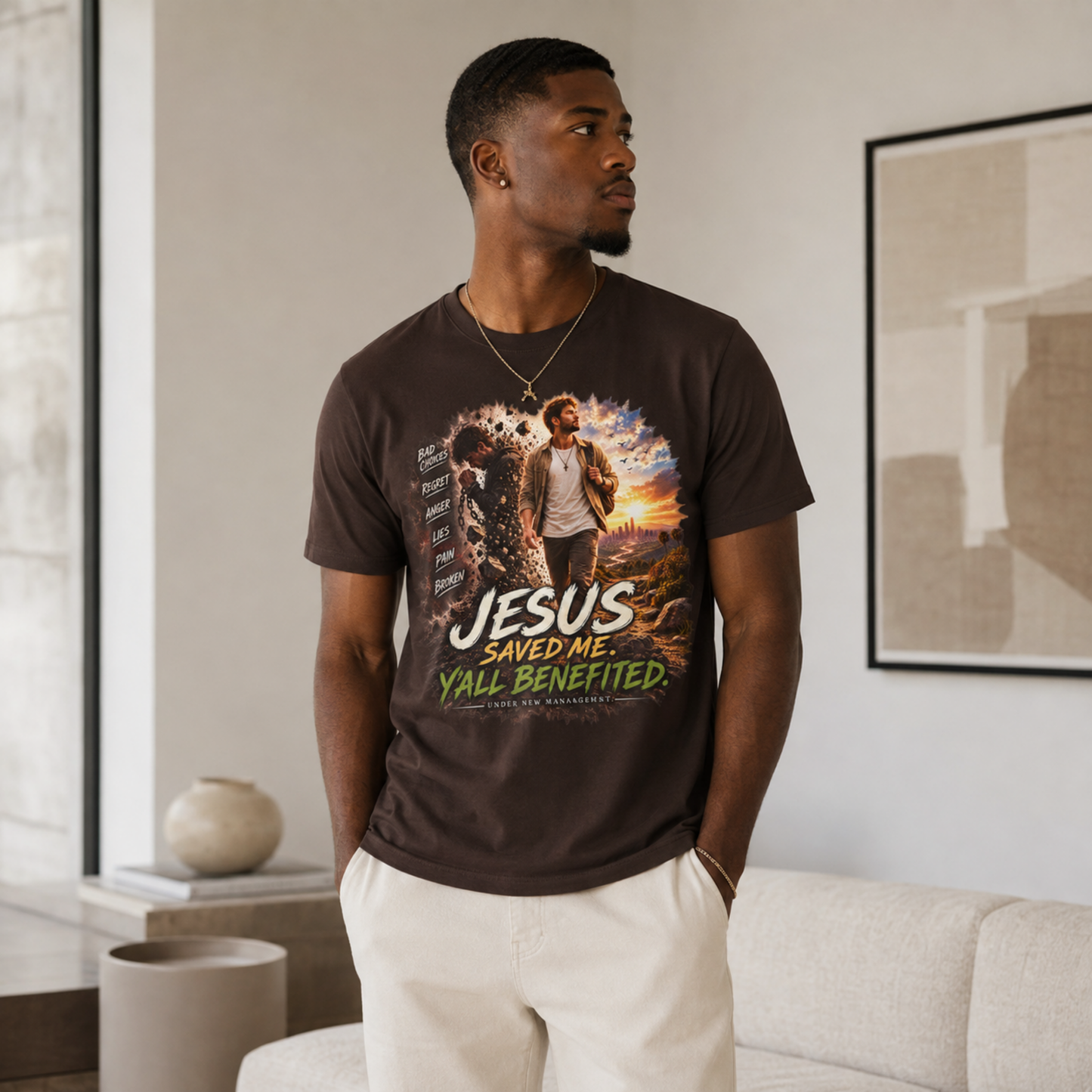 A man wearing a dark brown graphic t-shirt with the text 'JESUS SAVED ME. Y'all BENEFITED.
